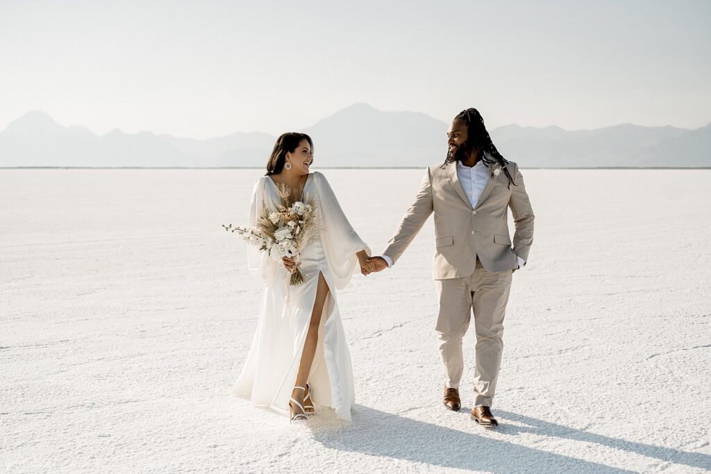 Utah elopement photographer captures bride and groom holding hands during salt flats wedding