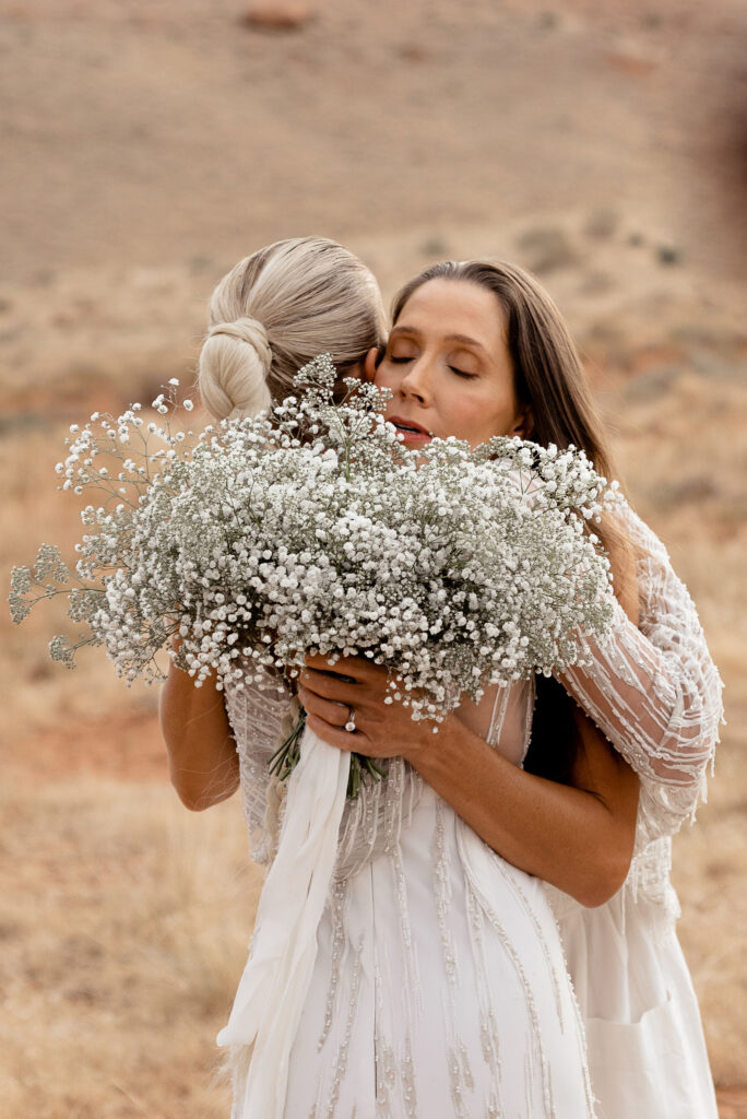 Moab elopement photographer captures bride hugging best friend 