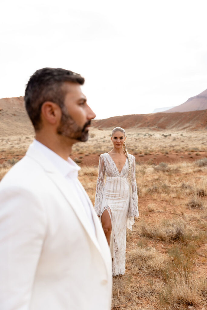 Moab elopement photographer captures groom standing and bride standing behind him