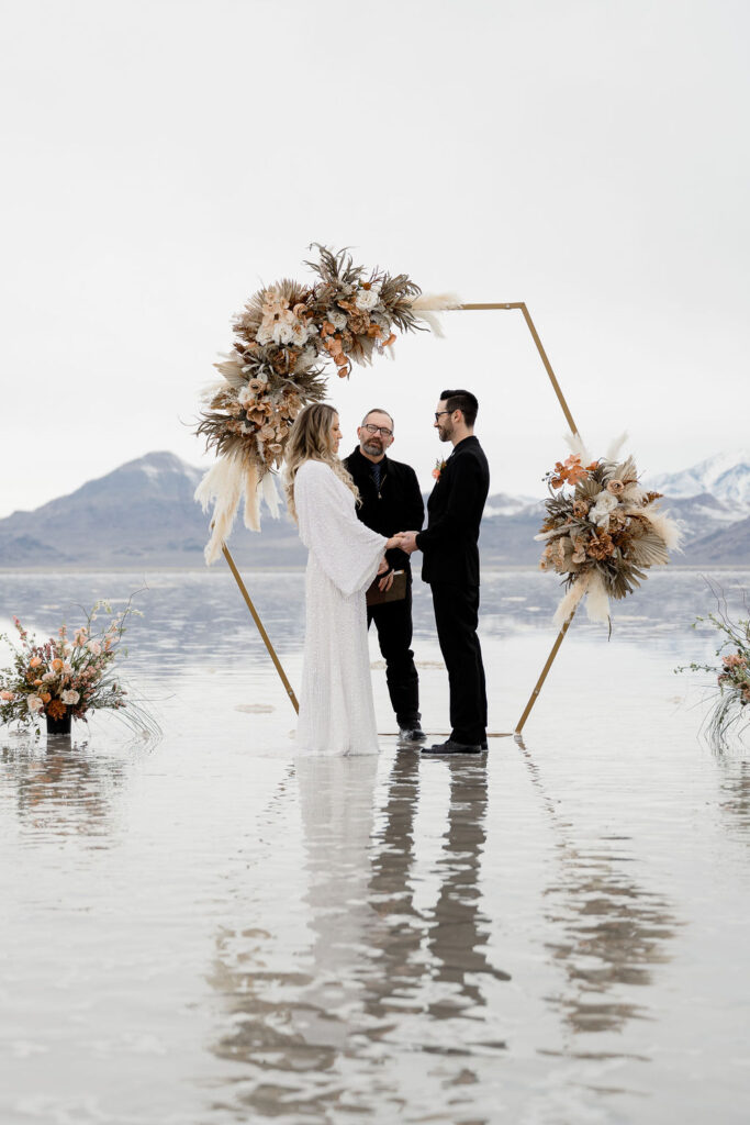 Utah elopement photographer captures bride and groom during wedding ceremony at flooded salt flats