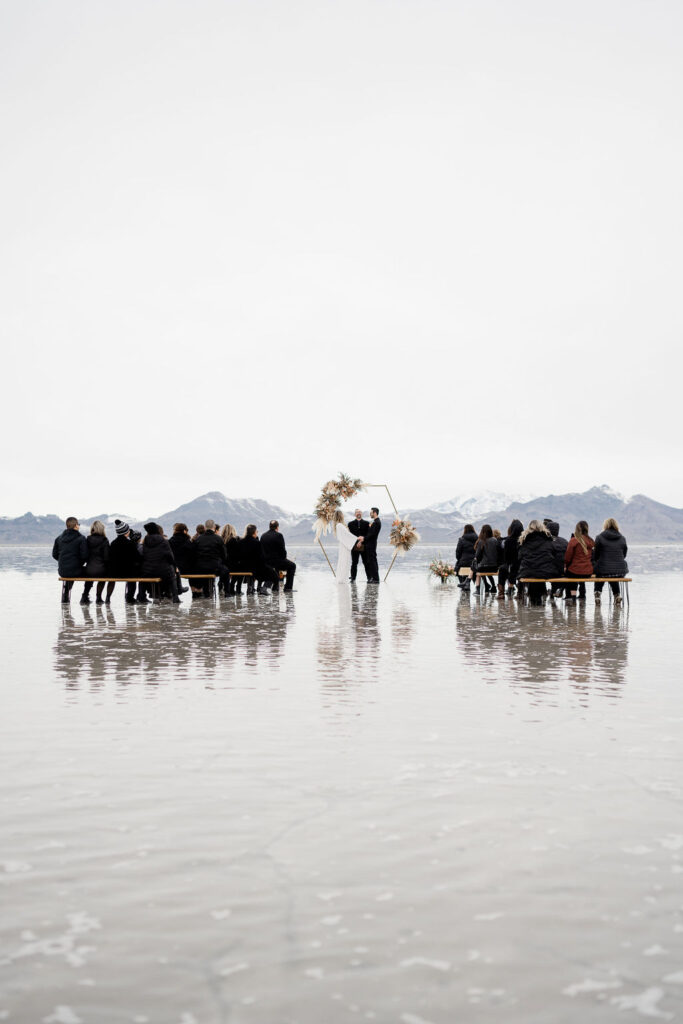 Utah elopement photographer captures couple walking through flooded salt flats in wedding attire