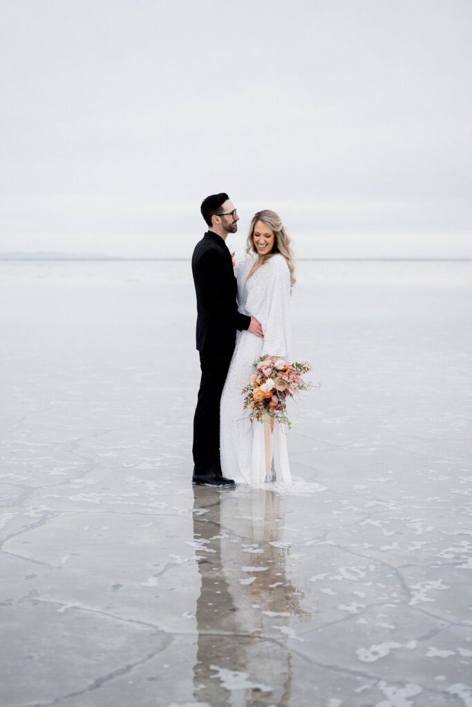 Utah elopement photographer captures couple embracing in flooded salt flats bridal portraits