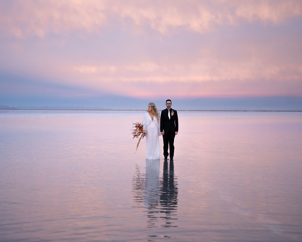 couple holding hands in flooded salt flats during blue hour