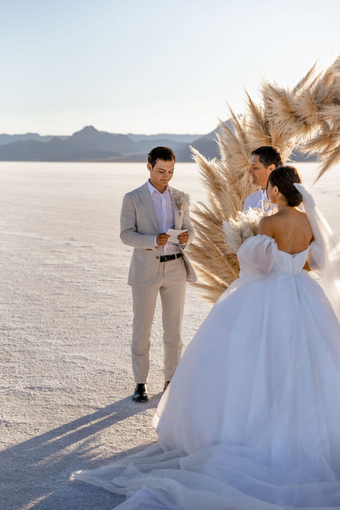 Utah elopement photographer captures groom reading vows at luxurious Salt Flats wedding