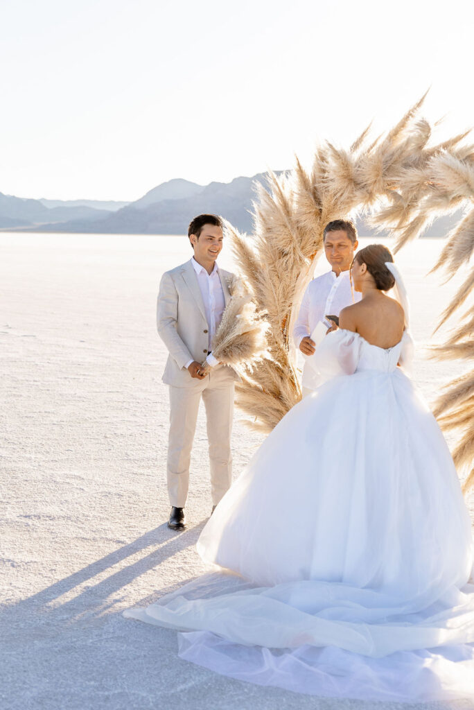 Utah elopement photographer captures groom holding bride's boho bouquet during bride's vows