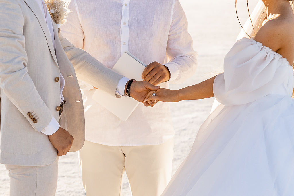 Utah elopement photographer captures bride and groom holding hands during luxurious salt flats wedding
