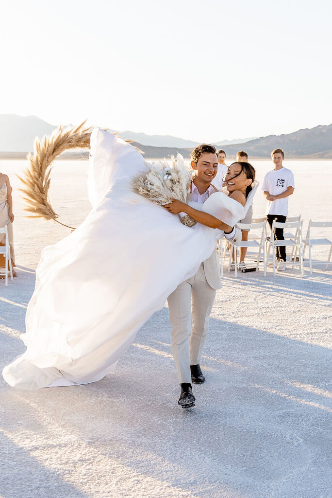 Utah elopement photographer captures groom carrying bride out of wedding ceremony