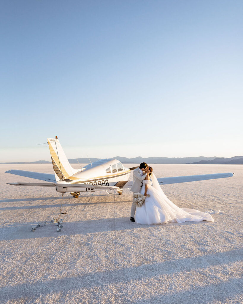 Utah elopement photographer captures couple standing by airplane kissing after luxurious salt lake wedding
