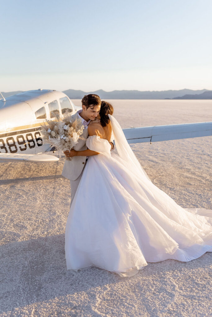 Utah elopement photographer captures couple hugging in front of airplane