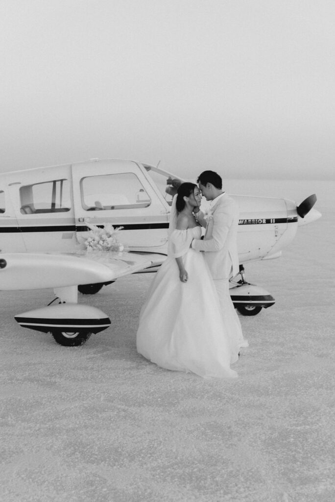 Utah elopement photographer captures bride and groom standing by airplane