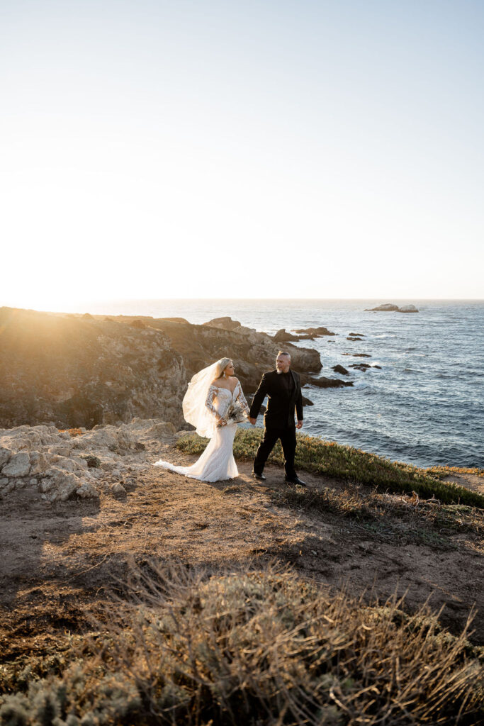 Big Sur elopement photographer captures bride and groom walking on the cliff