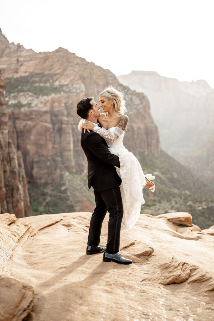Utah elopement photographer captures groom lifting bride during canyon bridals