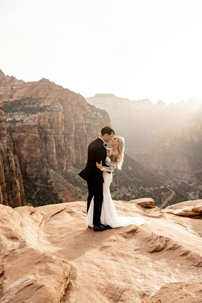 Utah elopement photographer captures couple kissing on top of cliff in Zion National Park