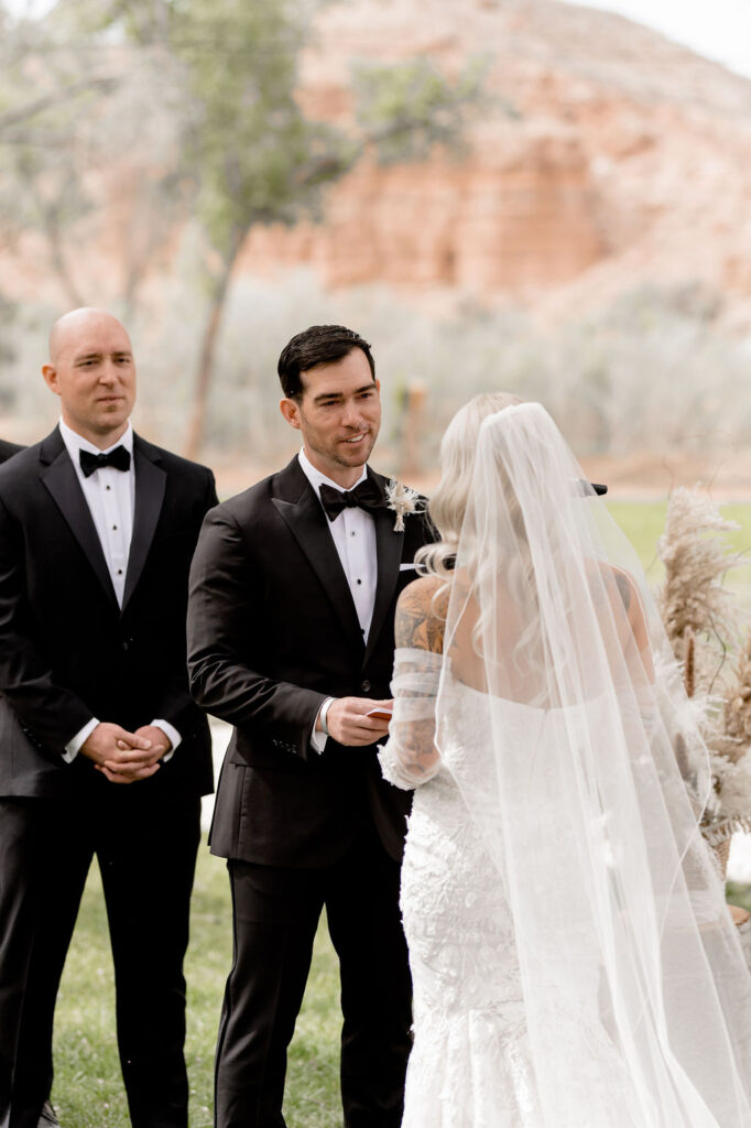 Utah elopement photographer captures groom looking at bride while she reads vows