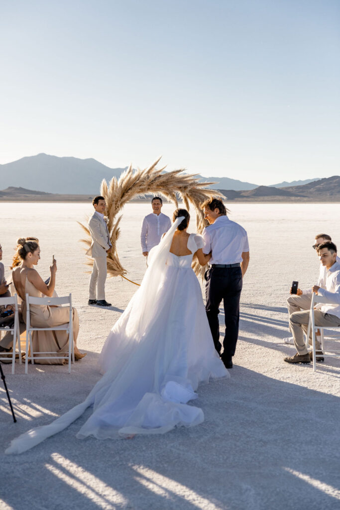 Utah elopement photographer captures bride being walked down aisle by father on Salt Flats wedding day