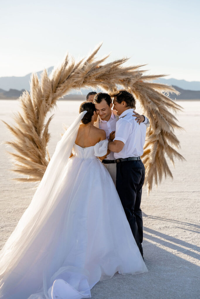 Utah elopement photographer captures bride being walked down aisle by father while groom hugs them both