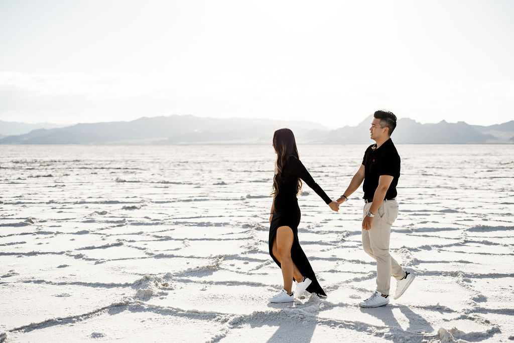 Utah elopement photographer captures couple walking hand in hand during classic salt flats engagements