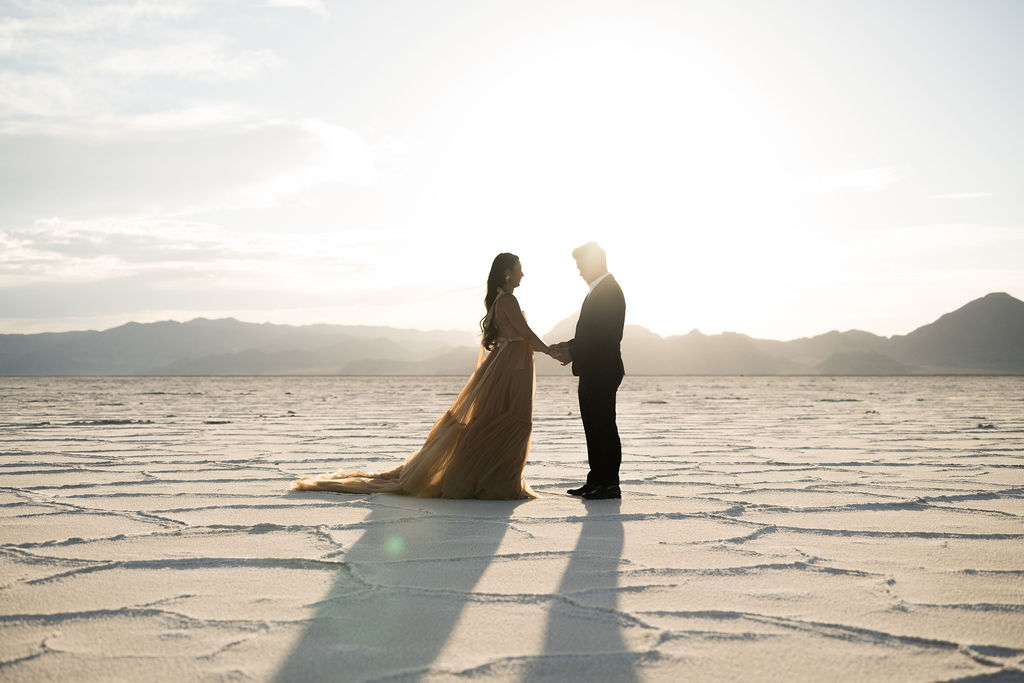 Utah elopement photographer captures couple holding hands at sunset during classic salt flats engagements