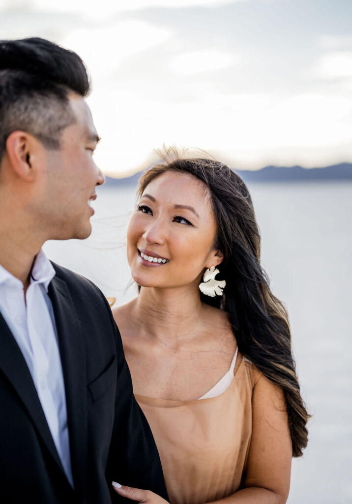 Utah elopement photographer captures woman looking at man during classic salt flats engagements