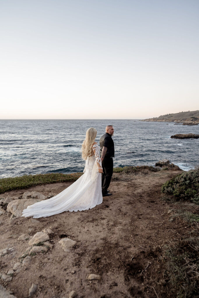 Big Sur elopement photographer captures bride and groom walking alongside the ocean