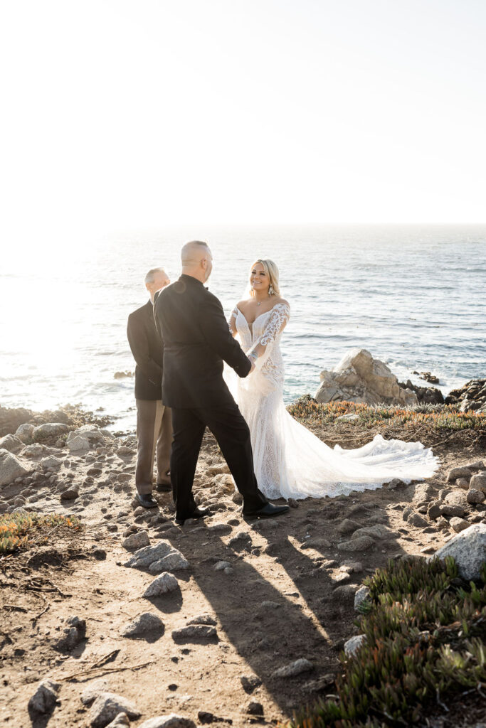 Big Sur elopement photographer captures bride and groom holding hands during elopement ceremony
