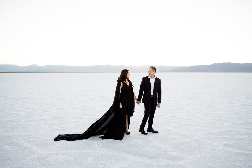 couple at the salt flats at sunset in black suit and dress