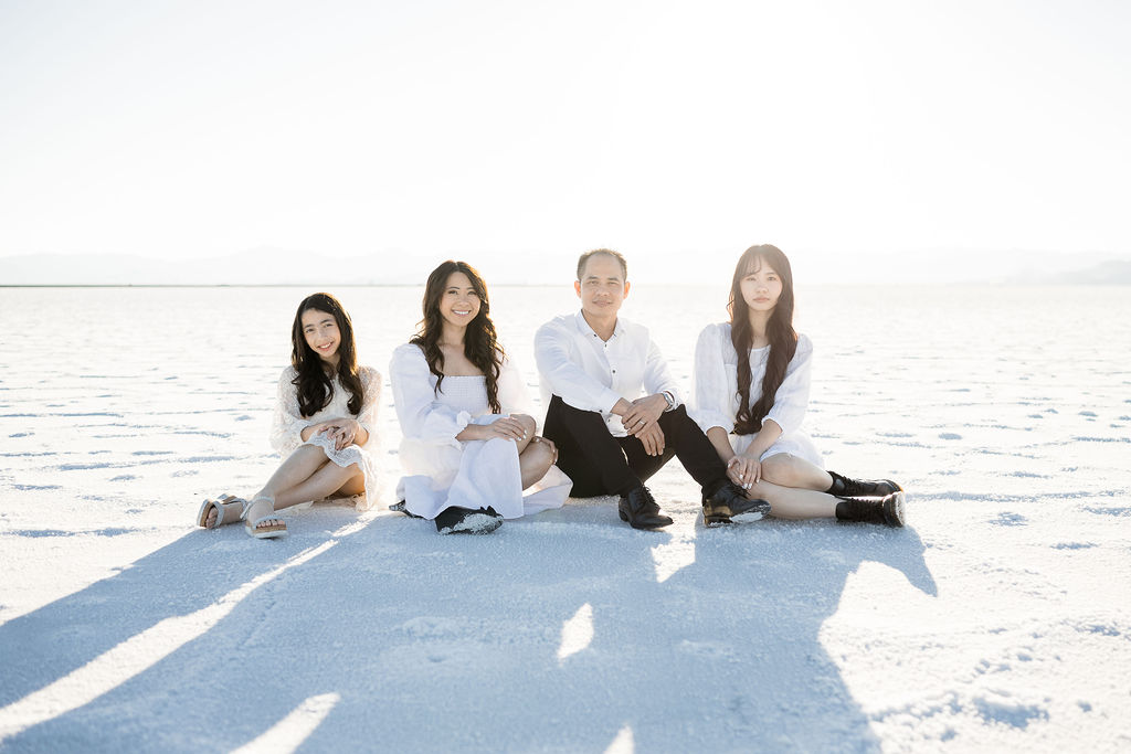 family photos at the salt flats in white, sitting on the ground at sunset