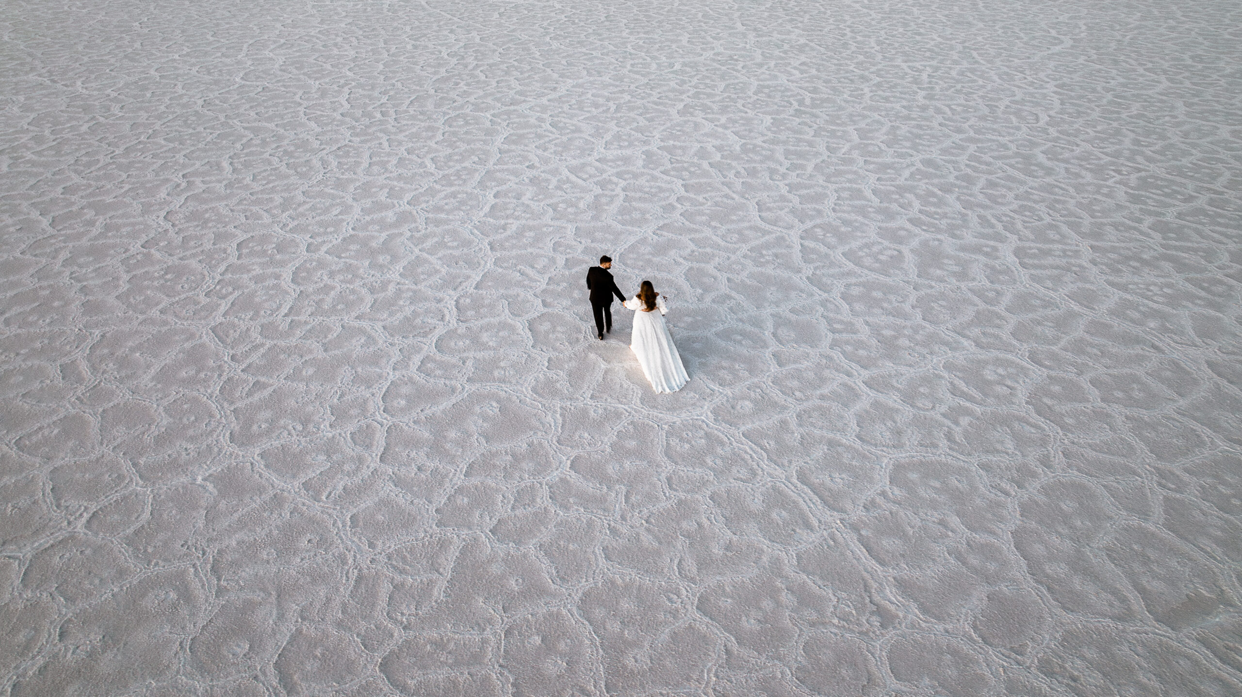 Drone photo of a Couple walking on the Textured Bonneville Salt Flats in utah