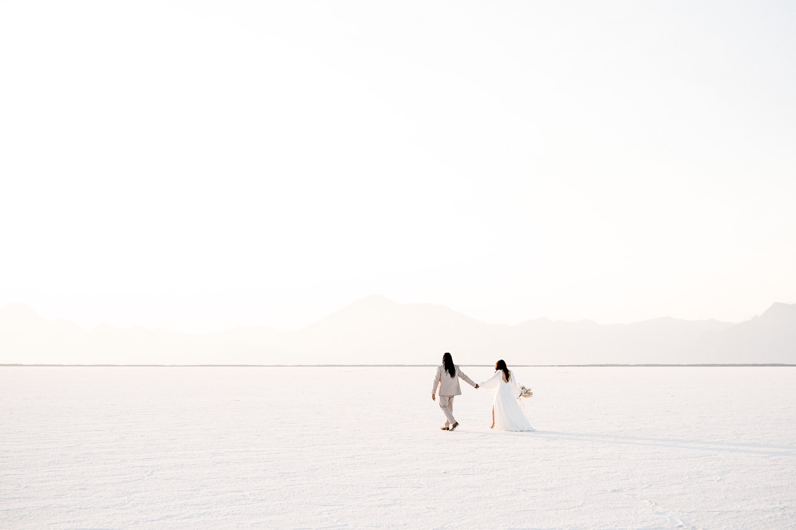 Couple Eloped at Salt Flats Utah Couple holding hands walking into the sunset