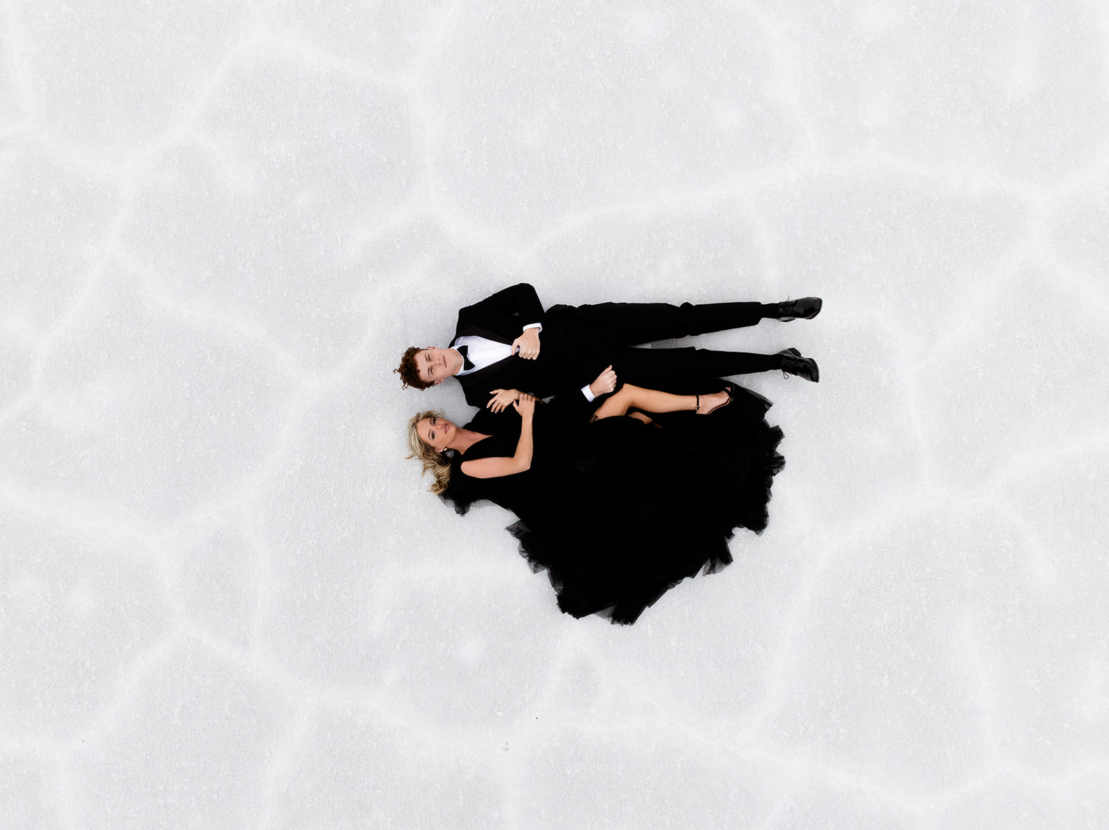 The newlyweds lay on the salt flats at sunset for a drone photo.