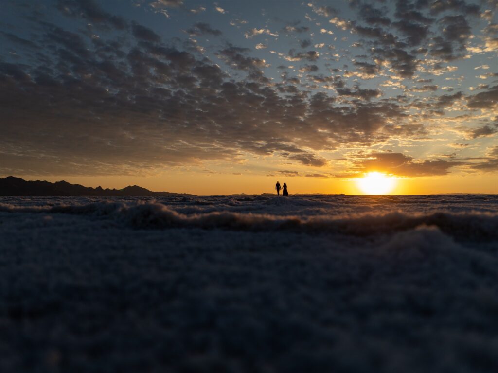 Bride and groom hold hands as the sun sets over the Salt Flats elopement venue.