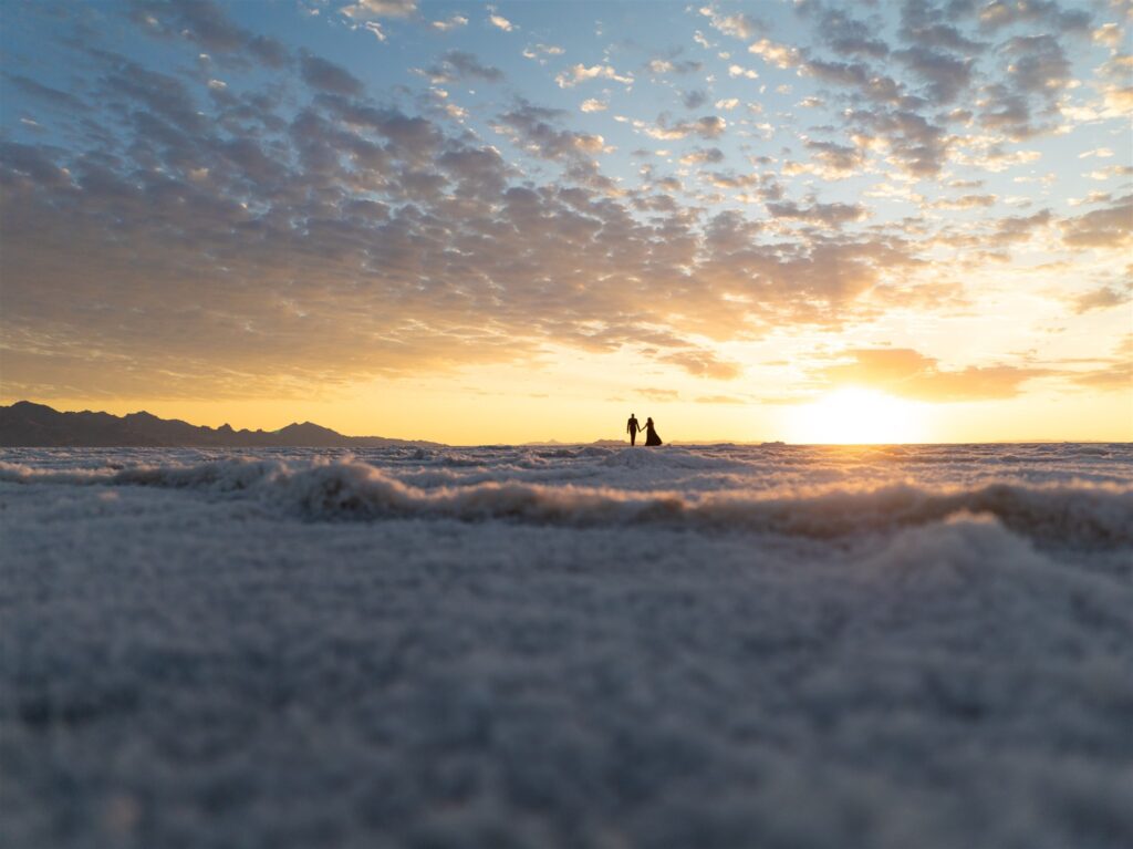 Silhouetted couple kissing under a vibrant Bonneville Salt Flats sunset.