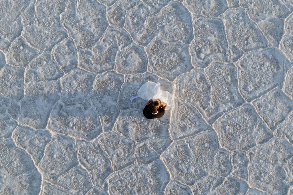 Aerial shot of a bride and groom surrounded by the vast Bonneville Salt Flats.