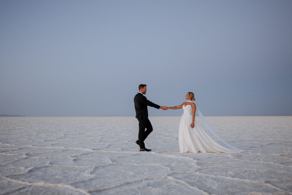 Couple holds hands on the Salt Flats in Utah as they elope.