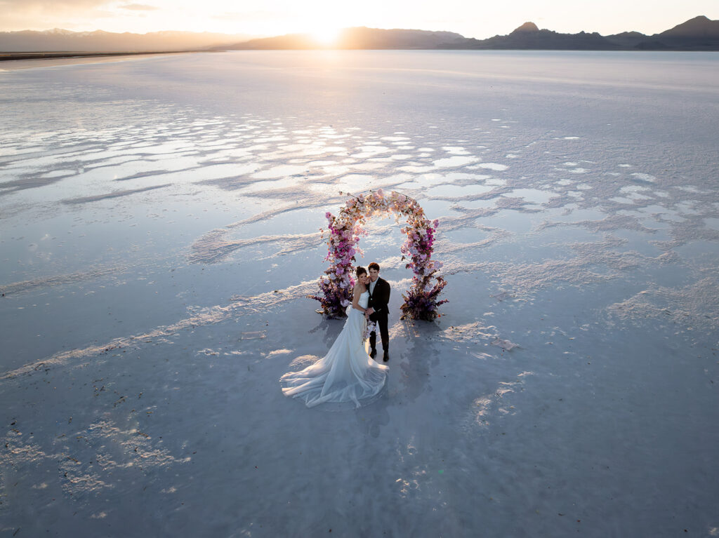 Bride and groom posing on reflective Salt Flats surface during golden hour in Utah.