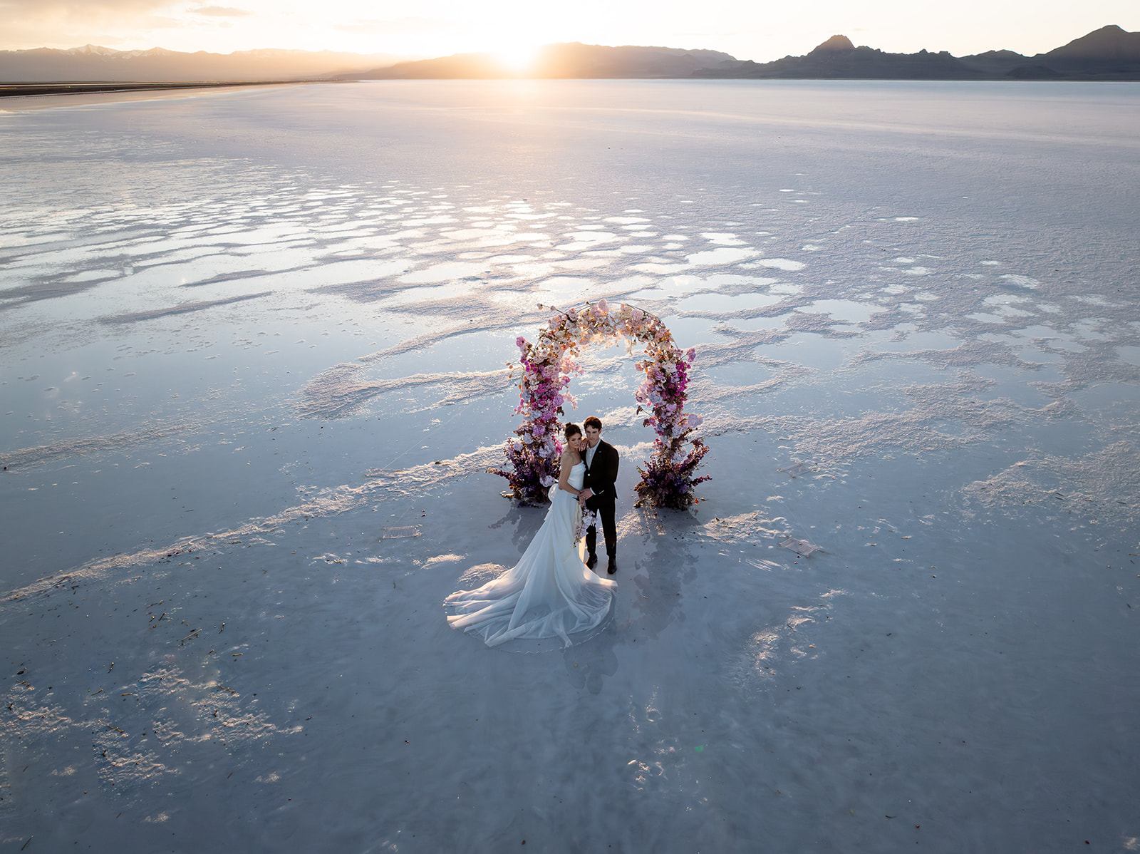 Bride and groom posing on reflective Salt Flats surface during golden hour in Utah.