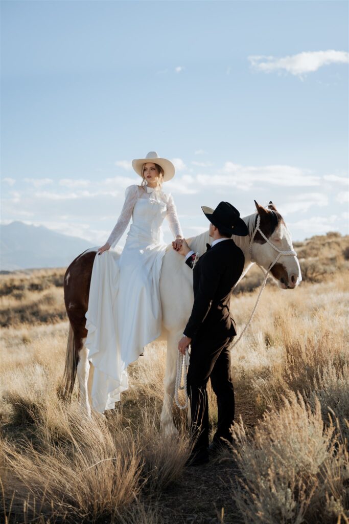 Bride on horse and groom holding brides hand on the horse during western elopement in Utah