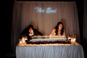 Bride and groom blowing out candles on the long dessert table at their candlelit Park City wedding reception